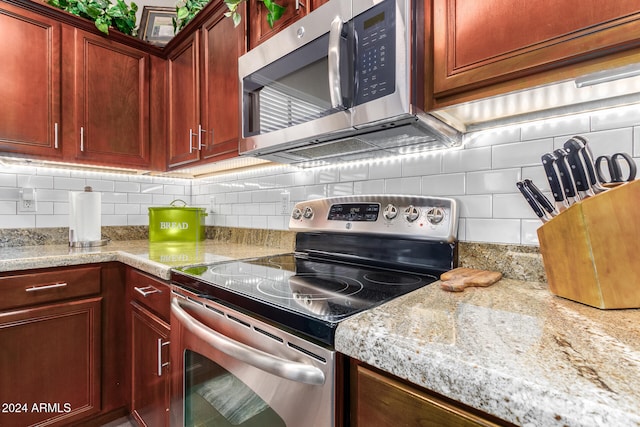 kitchen with light stone counters, decorative backsplash, and appliances with stainless steel finishes