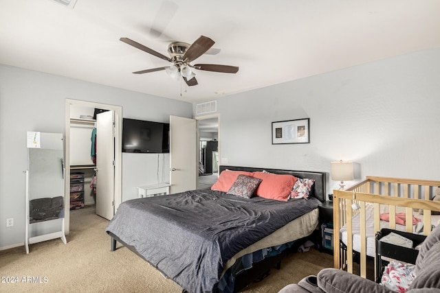 carpeted bedroom with ceiling fan, a closet, and a walk in closet