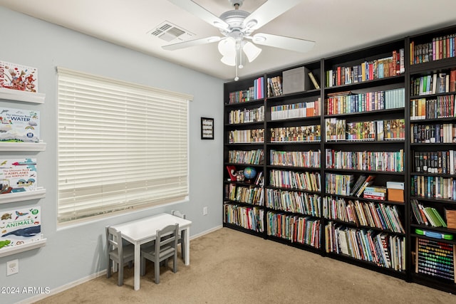 living area featuring light colored carpet and ceiling fan