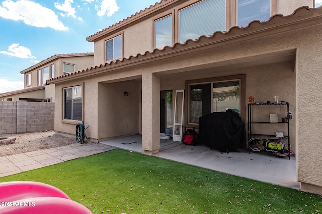 back of house with a patio area and a lawn