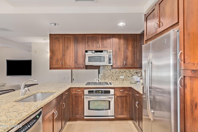 kitchen with sink, stainless steel appliances, tasteful backsplash, light stone counters, and light tile patterned floors