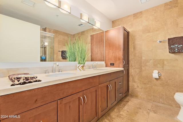 bathroom with an enclosed shower, vanity, toilet, and tile walls