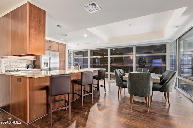 kitchen with dark hardwood / wood-style floors, light stone counters, appliances with stainless steel finishes, and a tray ceiling