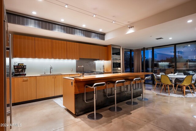 kitchen featuring sink, a kitchen island with sink, and double oven