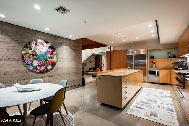 kitchen featuring built in appliances, a center island, and sink