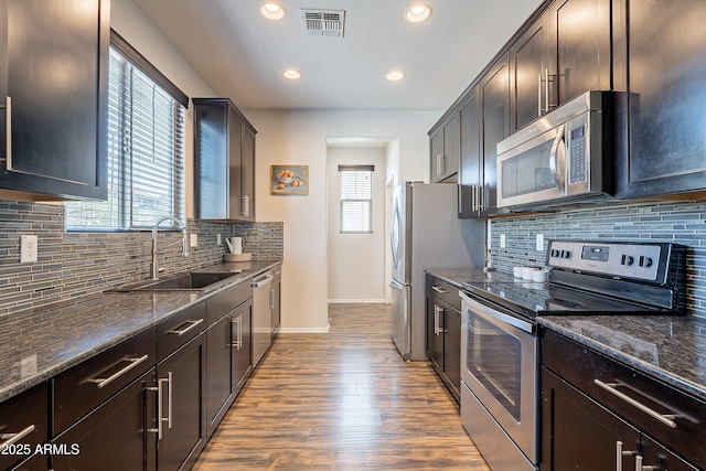 kitchen featuring plenty of natural light, visible vents, dark stone counters, stainless steel appliances, and a sink