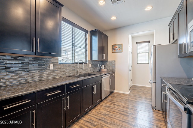 kitchen featuring dark wood-style flooring, a sink, a healthy amount of sunlight, appliances with stainless steel finishes, and tasteful backsplash