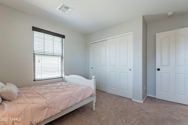 carpeted bedroom with a closet, visible vents, and baseboards