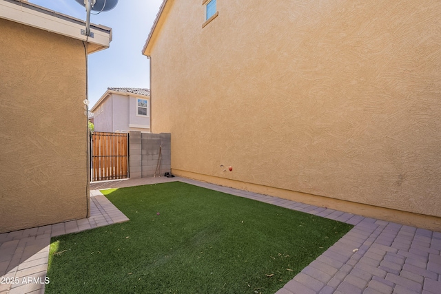 view of yard featuring a patio, fence, and a gate