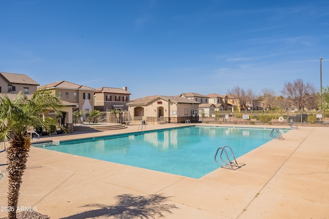 community pool with a patio area, a residential view, and fence