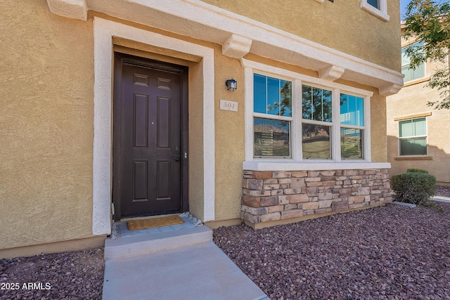 doorway to property with stone siding and stucco siding