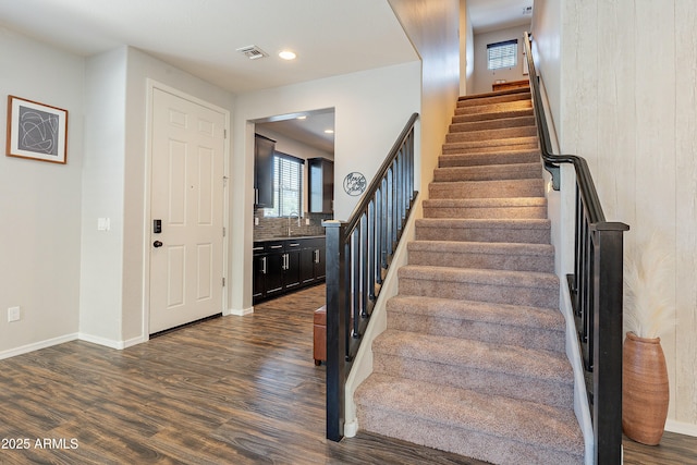 stairway featuring baseboards, visible vents, wood finished floors, and recessed lighting