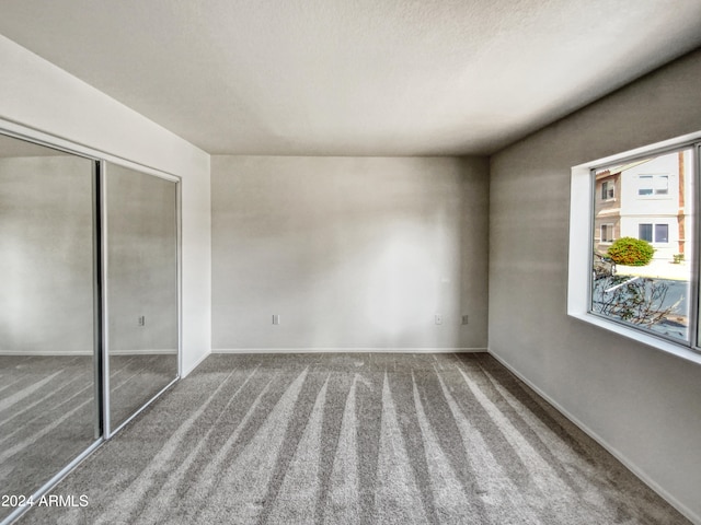 unfurnished bedroom featuring a closet, carpet floors, and multiple windows