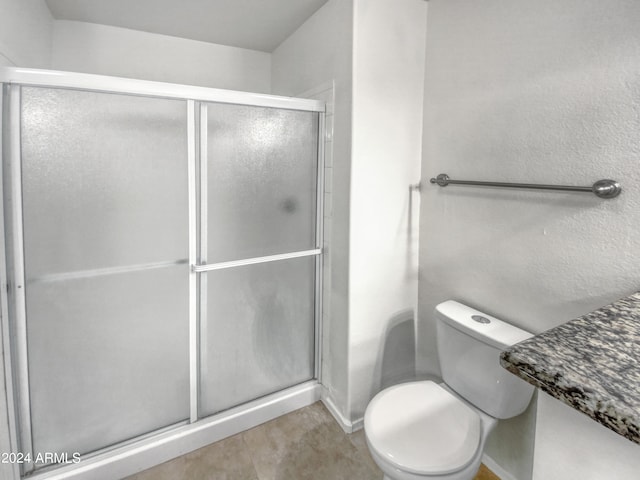 bathroom featuring tile floors, toilet, and a shower with door