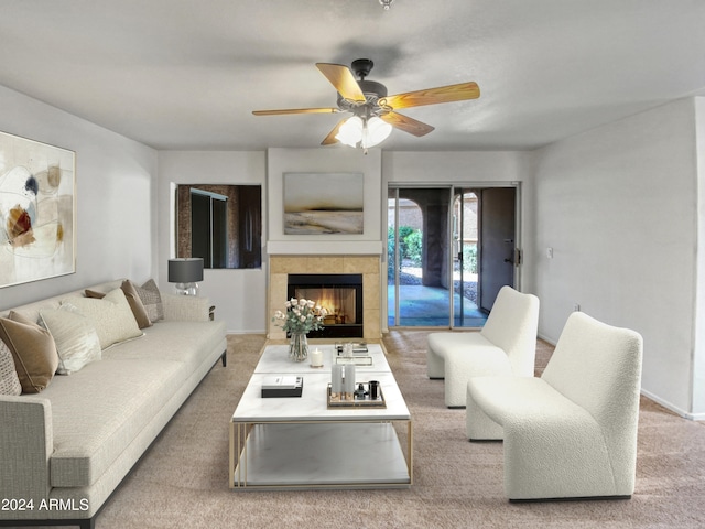 living room featuring a tiled fireplace, ceiling fan, and light colored carpet