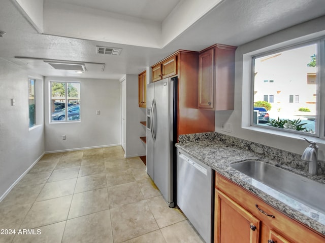 kitchen with sink, light tile floors, appliances with stainless steel finishes, and light stone counters