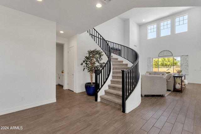 stairway with hardwood / wood-style flooring and a high ceiling