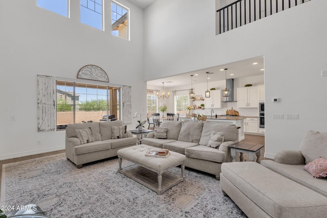 living room with sink, a towering ceiling, light hardwood / wood-style flooring, and a notable chandelier