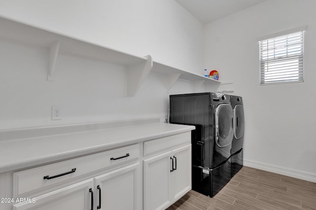 clothes washing area with cabinets, independent washer and dryer, and light wood-type flooring