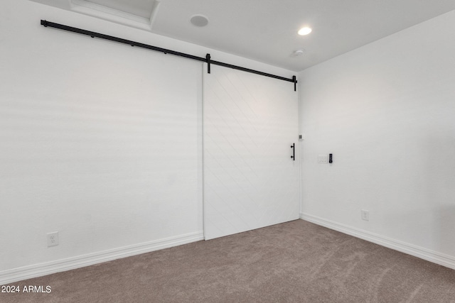 carpeted empty room with a barn door