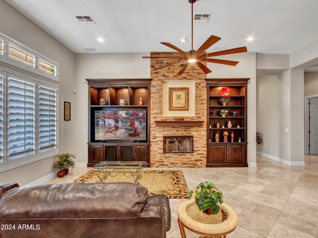 living room featuring a stone fireplace, ceiling fan, and built in features