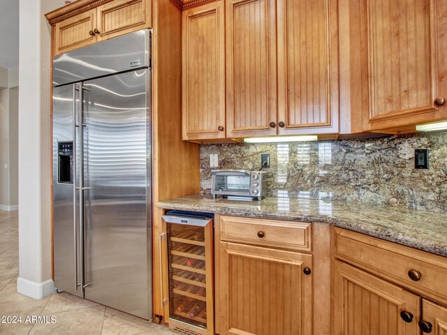 kitchen featuring light stone counters, sink, an inviting chandelier, stainless steel appliances, and a center island with sink