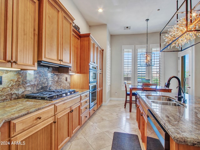 kitchen featuring a kitchen island with sink, sink, an inviting chandelier, backsplash, and appliances with stainless steel finishes