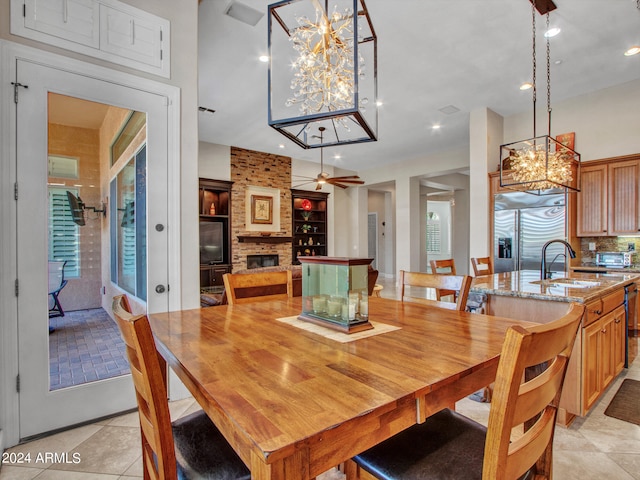 tiled dining area featuring an inviting chandelier, a large fireplace, and sink