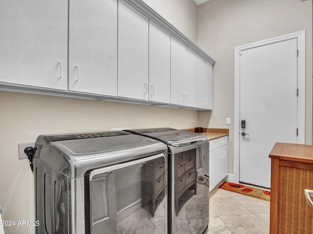 laundry room featuring cabinets, light tile patterned flooring, and washer and clothes dryer