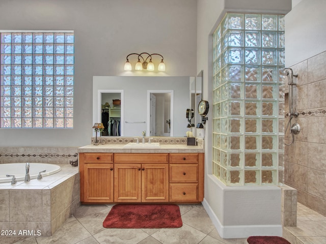 bathroom featuring plus walk in shower, tile patterned flooring, and vanity