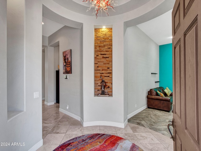 corridor with a notable chandelier and light tile patterned floors