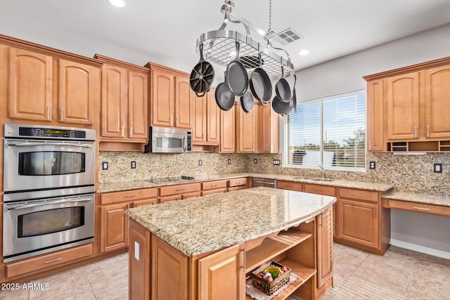 kitchen with backsplash, sink, light stone countertops, appliances with stainless steel finishes, and a kitchen island