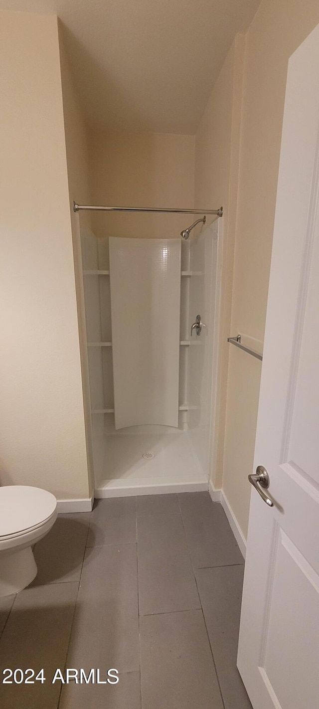 full bath with baseboards, a shower stall, toilet, and tile patterned floors