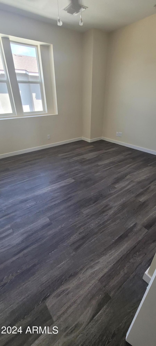 empty room with dark wood finished floors and baseboards