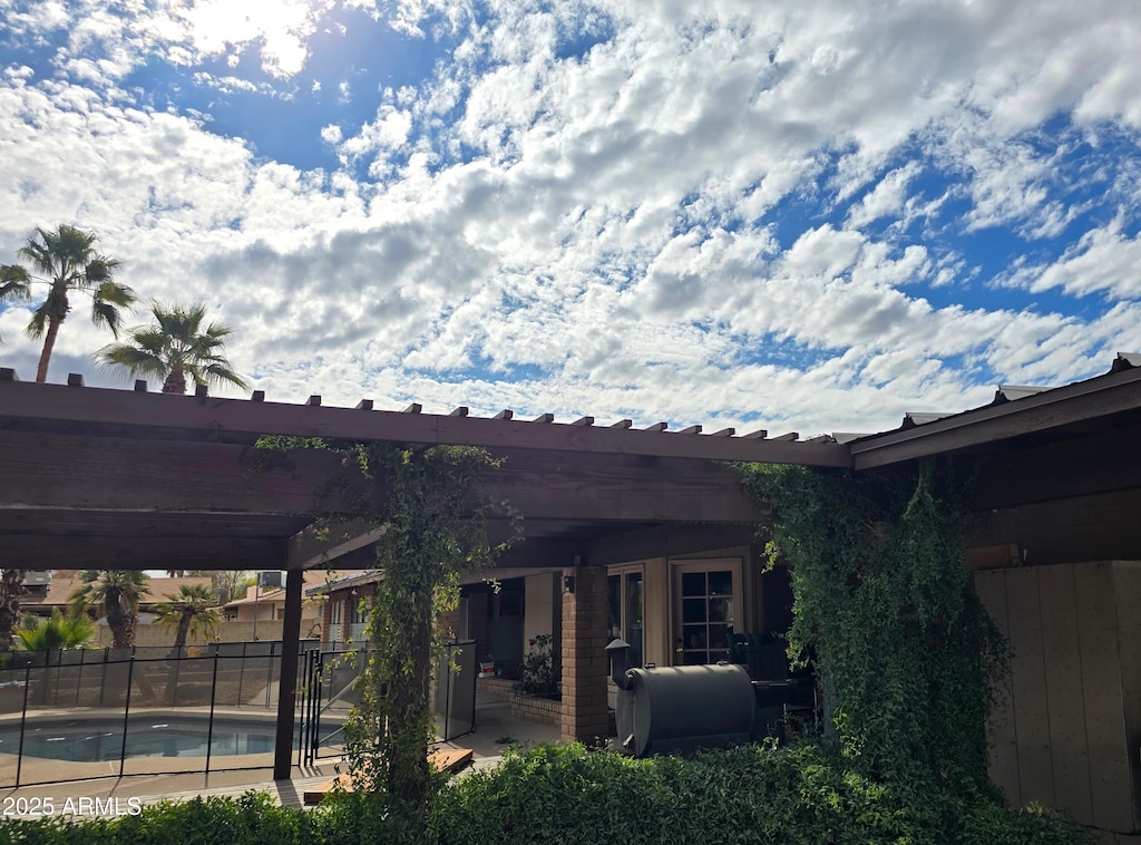 rear view of property featuring a fenced in pool, brick siding, a patio area, fence, and heating fuel