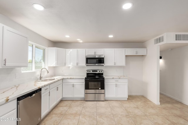 kitchen featuring a sink, visible vents, white cabinets, appliances with stainless steel finishes, and decorative backsplash