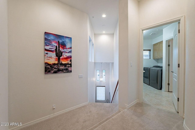 hall with washer and dryer and light carpet