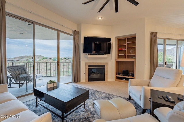 carpeted living room featuring built in shelves, plenty of natural light, and ceiling fan