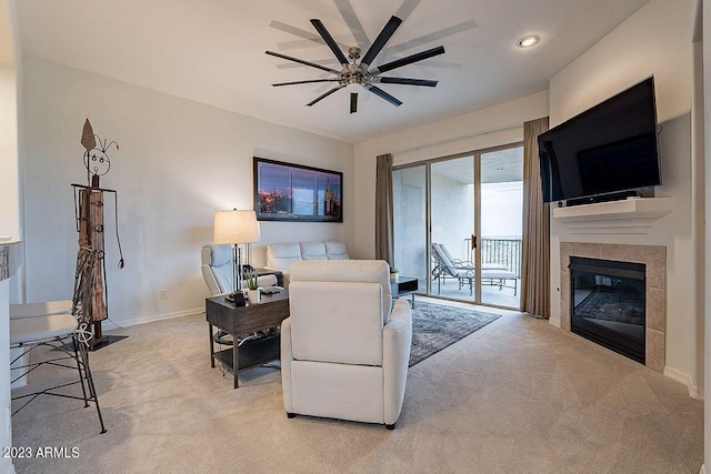 carpeted living room with a tile fireplace and ceiling fan