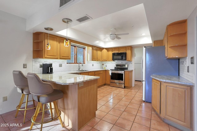 kitchen with a tray ceiling, kitchen peninsula, hanging light fixtures, and stainless steel appliances