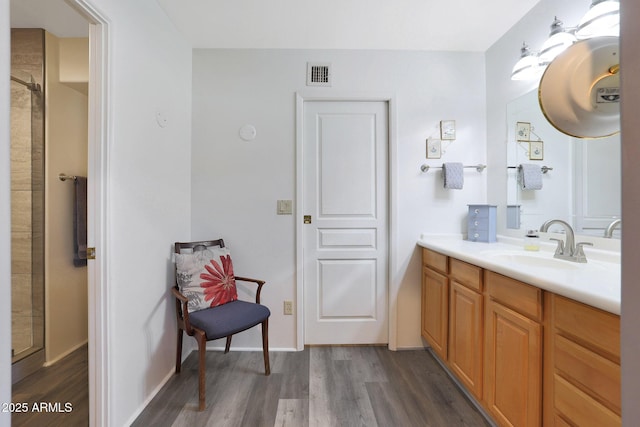 bathroom with hardwood / wood-style floors, vanity, and walk in shower