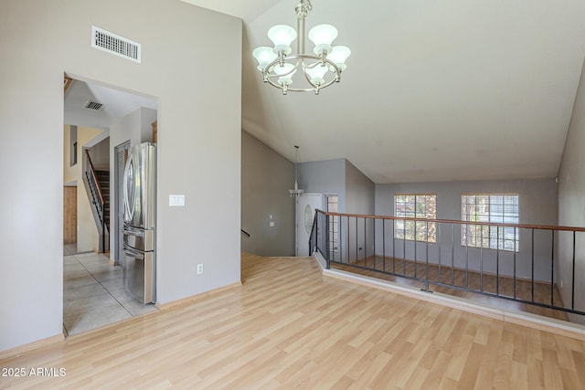 unfurnished room featuring visible vents, a notable chandelier, and wood finished floors