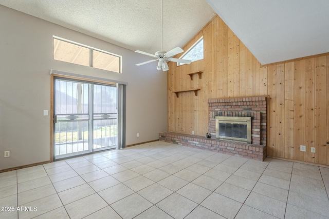 unfurnished living room with a brick fireplace, tile patterned flooring, wooden walls, and high vaulted ceiling