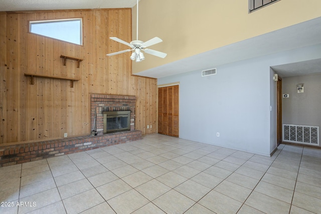 unfurnished living room with a brick fireplace, visible vents, and wood walls