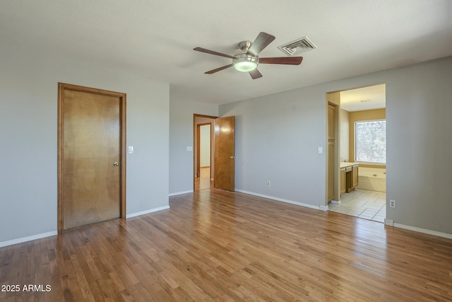 unfurnished bedroom featuring baseboards, connected bathroom, visible vents, and light wood-style floors