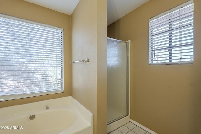 bathroom with a stall shower, tile patterned flooring, a bath, and baseboards