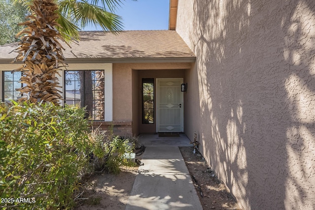 property entrance with a shingled roof and stucco siding