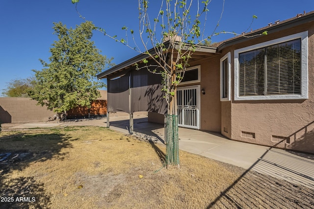 rear view of property with a patio, fence, and stucco siding