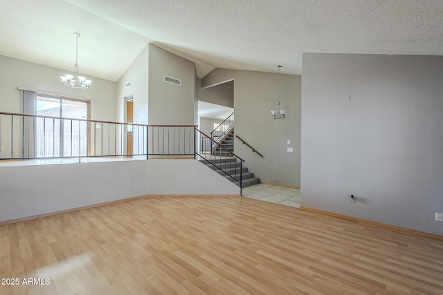 spare room with stairs, wood finished floors, visible vents, and a notable chandelier