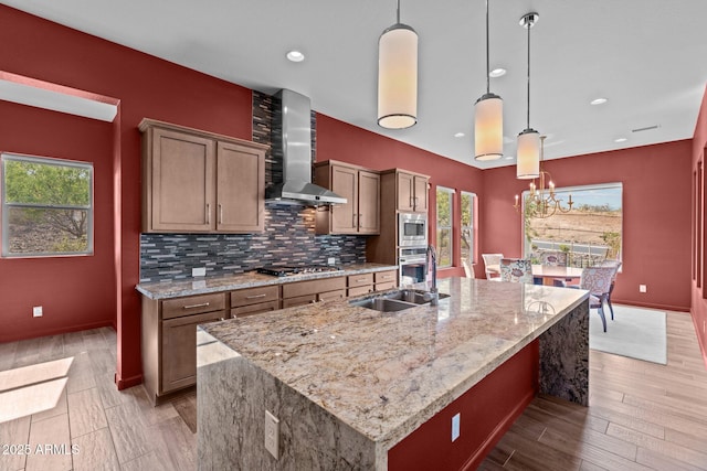 kitchen with a sink, stainless steel appliances, a wealth of natural light, and wall chimney exhaust hood